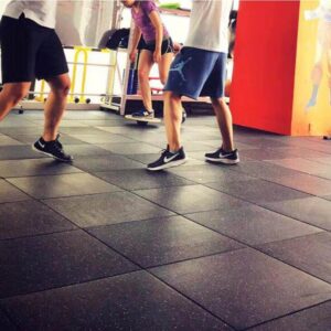 Black gym flooring mats with people stepping on it